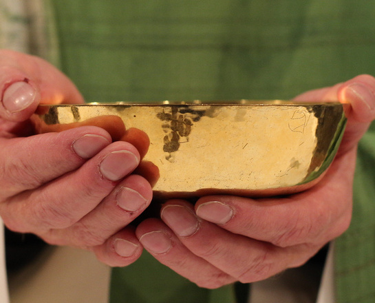 Wandlung Ein Priester hält eine Patene in der Hand.